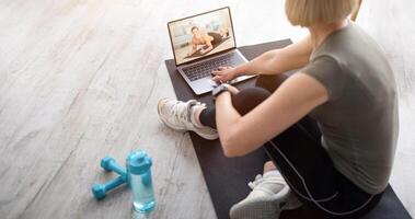 Senior woman watching online sports tutorial on laptop, taking break from her domestic training. Mature lady communicating to her personal trainer on web at home, copy space photo