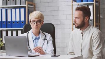 A dietitian advises a man patient about nutrition and dietary choices while seated at a desk in a contemporary clinic. The interaction focuses on lifestyle improvements and healthy eating. video