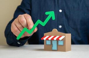 Shop and green arrow up. Business growth and expansion. Upward business momentum, rising profits, and market presence. Successful entrepreneurship, customer demand, brand scalability photo