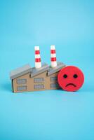 Industrial plant and sad face. Deteriorating financial situation and low expectations from forecasts. Pessimism in industrial sectors. Reduced investor confidence. photo