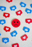 Sad face surrounded by likes and hearts from social networks. Chasing likes does not make you happy. Internet addiction, doomscrolling. Endorphin addiction. Emotional burnout in digital culture photo