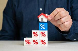 Man puts house on interest rate blocks. Mortgage flexibility, banking relief programs, loan restructuring. Credit holidays can ease financial strain during crises or inflationary periods. photo