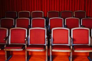 Rows of red upholstered chairs arranged in a theater setting for performance attendees photo