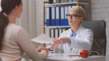 A healthcare professional discusses nutrition with a lady patient in a modern clinic. The dietitian is reviewing dietary plans and providing guidance on healthy eating choices. video