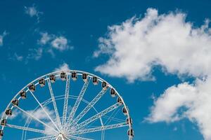 Ferris wheel against a clear blue sky with fluffy white clouds in the afternoon photo