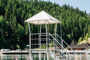 Lifeguard tower overlooking a tranquil lake surrounded by lush greenery during summer photo