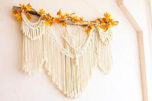 Macrame wall hanging decorated with autumn leaves in a cozy indoor setting photo
