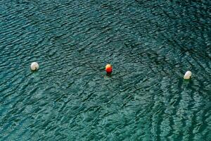 Colorful buoys floating on calm water with ripples in a serene coastal environment photo