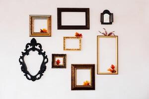 Wall display of empty frames with autumn leaves in a cozy interior setting photo