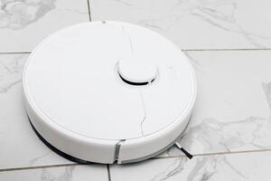 Robot vacuum cleaner operates on tiled floor during a bright afternoon in a modern home setting photo