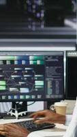 Vertical Data center admin using artificial intelligence neural network models to configure hardware. Man works on AI programming language in server room, optimizing system functionality, camera B video