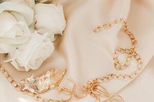 Elegant gold chain and rose arrangement on soft fabric during a romantic event preparation photo