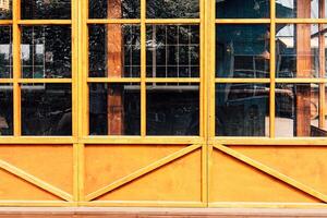 Bright yellow wooden window frames showcase the exterior of a rustic building in daylight photo