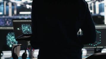 Data center programmer entering office uses node tree program to identify equipment performance issues. Server hub worker sitting at desk, reviewing data analysis graph to minimize failures, camera B video