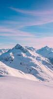 Scenic snow-capped mountains stand majestically under a pastel blue sky, creating a serene winter landscape with soft colors. photo