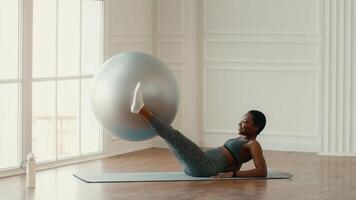 A woman is engaged in an effective workout at home, using a stability ball to strengthen her core. She appears focused and determined while practicing her fitness routine indoors. video