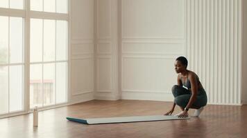 African American woman practices her fitness routine at home. She performs a workout on a yoga mat, emphasizing a healthy lifestyle in a well-lit indoor space. video