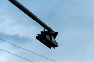 A traffic signal hangs overhead, positioned strategically to manage vehicle movement during overcast weather, showing clear skies in the background photo
