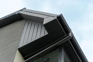 View of a contemporary building highlighting a sharp roofline, metallic siding, and large windows, showcasing modern architecture against a clear sky photo