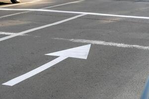 A clear view of white road markings on asphalt shows directional arrows and lines guiding vehicles. This image captures a well-maintained urban street scene photo