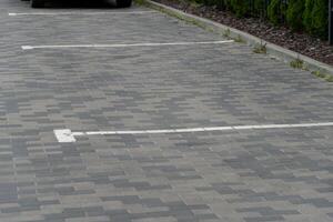 Unoccupied parking lot features outlined spaces on a paved surface, showcasing a clean and quiet urban environment with patches of grass along the edges photo