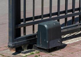 A close-up view of an automatic gate mechanism reveals the motor and tracks used to operate the gate at a commercial property during daytime photo