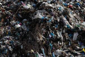 A sprawling mound of various types of waste dominates an urban landfill site, illustrating the significant environmental impact of human activities and waste management issues photo