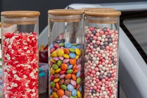 Brightly colored jars filled with assorted candies and sweets are showcased at a lively market, attracting visitors with their vibrant hues and enticing appearance photo