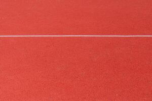 A vibrant red surface designed for athletic activities highlights the area where runners will compete. This track is suitable for various sports events photo
