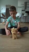 7 year old boy playing cubes on the floor, building a tower. Tower breaks video