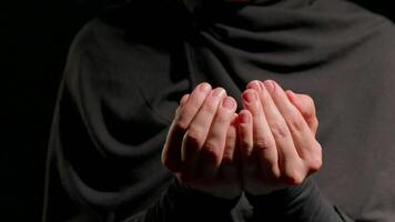 woman wearing hijab is seen her hands in prayer position. dimly lit background creates serene and reflective atmosphere conveying sense of spirituality and peace video
