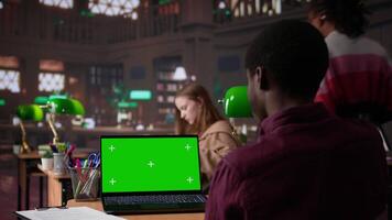 Young student working with a green screen in the university campus library, collecting academic information from verified educational sources. Pupil using research tools. Camera B. video