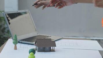 A person is pointing at a laptop with a model of a house video