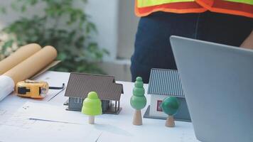 A man is working on a laptop and a model of a house video