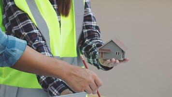 A man and woman are holding a miniature model of a house video