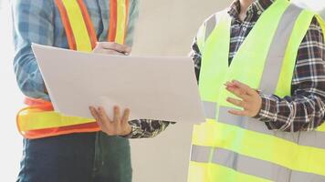 Two construction workers are holding papers and looking at each other video