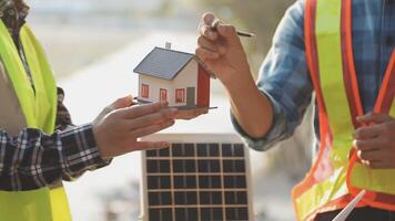 Two men holding a model of a house with solar panels video