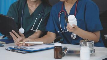 Two female doctors in scrubs sitting at a table with tablets video