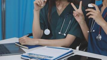 Two women in scrubs sitting at a table with laptops video