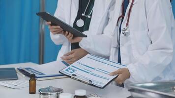 Two doctors are looking at a tablet while standing in front of a desk video