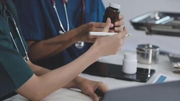 Two doctors are working on a laptop and holding a bottle video