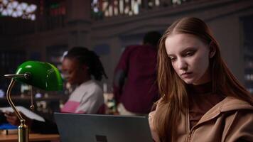 Student struggling to stay focused and awake while she does her research, writing on bachelor paper in the library to obtain college diploma. Girl working hard for a certificate. Camera B. video