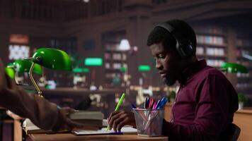 Black guy using study music to help with deep focus for academic success, consulting the campus university database to find reliable sources. Male college student fights for diploma. Camera A. video