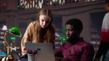 Multiethnic pupils working on team project assignment at campus library, consulting academic database and research collection with various books. Young adults guarantee high grades. Camera A. video