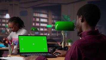 Faculdade aluna parece às uma cópia de espaço em computador portátil enquanto colecionar notas a partir de confiável acadêmico fontes, consultando a campus biblioteca livros coleção para a atribuição. aluna vida. Câmera uma. video