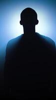 silhouette of a man posing in dark space with bright backlight. Vertical shot video