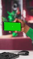 Vertical African american man engaging with AI chatbot next to chroma key, using the virtual assistant with prompts for data driven algorithms to enhance productivity at home office. Camera A. video