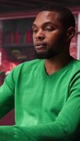 Vertical African american remote worker solving daily job assignments, finishing his tasks online from the comfort of his modern loft. Young adult teleworker connected on web, multitasking. Camera A. video