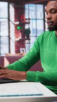 Vertical Man at home deals with back pain and stretching joints on chair, being uncomfortable due to incorrect posture. Black guy feeling overworked and experiencing muscle cramps at desk. Camera B. video