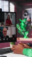 Vertical Remote worker looking at PC monitor discussing with coworkers during videocall from home. Computer display used by teleworker in remote teleconference meeting with colleagues. Camera A. video